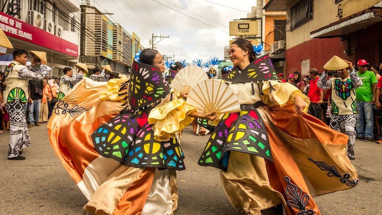 Dancers in stained-glass-motif costumes performing in the street during the Peñafrancia festival in Naga City
